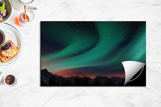 Een afdekplaat voor inductiekookplaat met een afbeelding van het Noorderlicht boven een berglandschap.