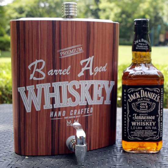Drankdispenser met houtennerfprint en tekst 'PREMIUM Barrel Aged WHISKEY HAND CRAFTED'. Naast een fles Jack Daniel's. Buitenopname.
