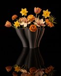 Zes zwarte, 3D-geprinte vazen met golvende vormen, gevuld met oranje en gele bloemen.