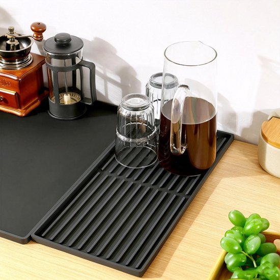 Zwarte siliconenmat met afneembaar rooster, met glazen karaf met koffie en glazen.