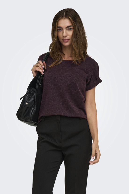 Model draagt donkerpaarse top met korte mouwen, glitterdetails en zwarte broek.