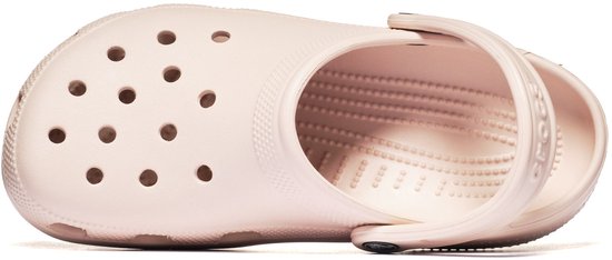 Boven-aanzicht van een lichte roze Crocs clog, liggend op zijn kant. De schoen heeft perforaties aan de bovenkant.