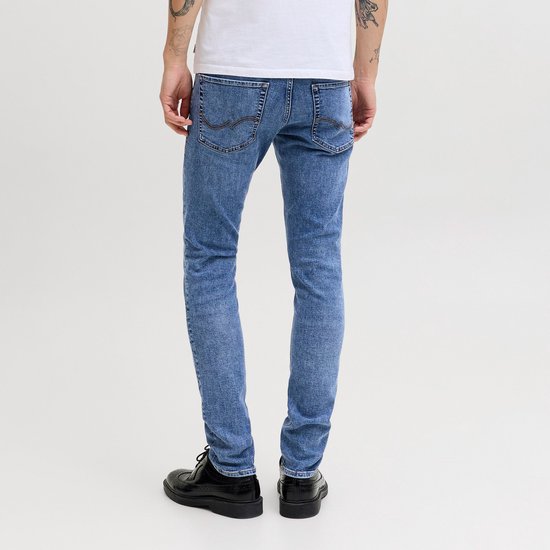 Man met slanke blauwe jeans en zwarte schoenen, achterkant.