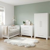 Witte babykamer met ledikant, commode en kast in een kamer met mosgroene muur.