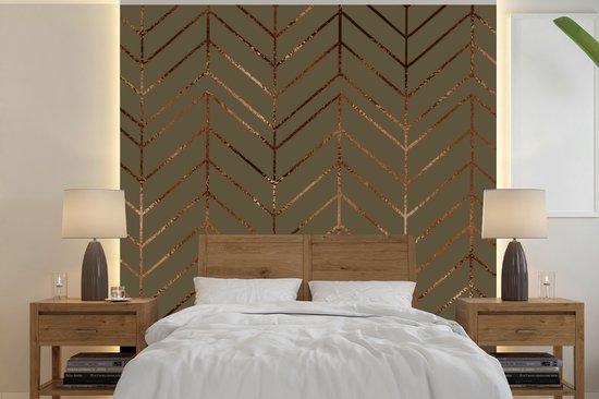 Groen behang met bronzen visgraatmotief, boven een houten hoofdeinde.
