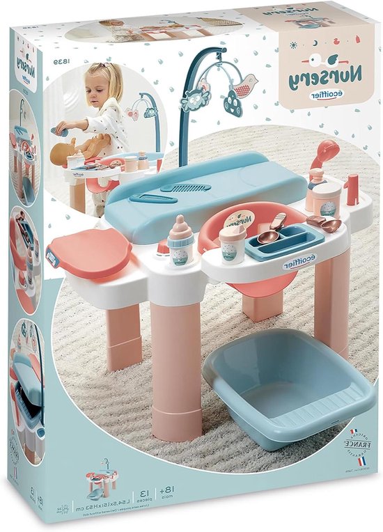 Verpakking van een poppenverzorgingsset in zachtroze en lichtblauw met afbeeldingen van accessoires en een kind.