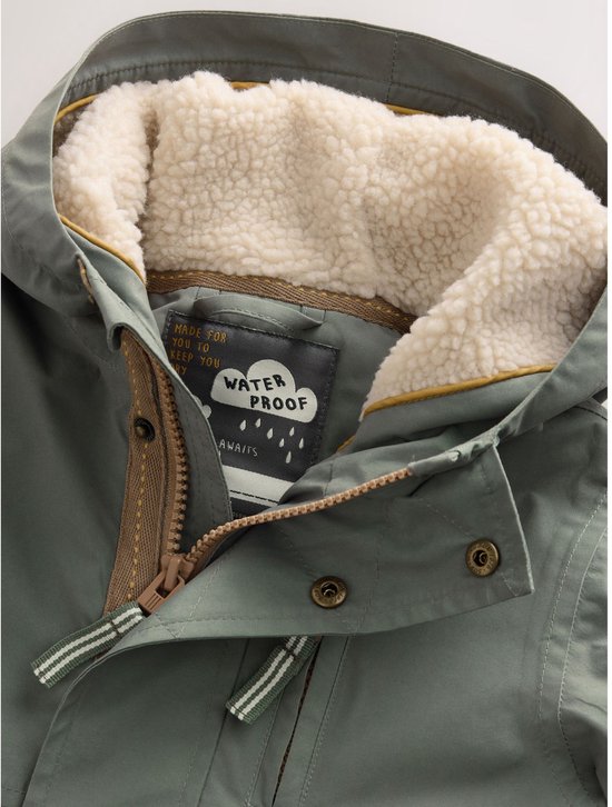 Detailopname van de capuchon en kraag van een groene parka, gevoerd met crèmekleurige imitatiebont, met label 'Waterproof'.