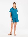 Model met een turquoise korte broek en bijpassend shirt met korte mouwen.