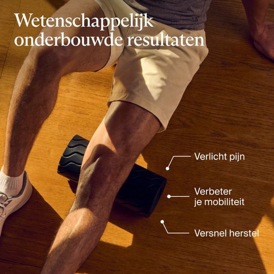 Close-up van een man die een zwarte schuimroller met golftextuur gebruikt voor pijnbestrijding en mobiliteit.