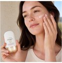 Vrouw met bruin haar brengt Lancaster Sun Perfect AIR SPF 50 Mineral sensitive aan op haar wang, terwijl ze de tube vasthoudt.