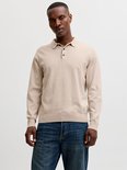 Man, lichtbeige gebreid poloshirt met lange mouwen, twee zwarte knoopjes en donkerblauwe jeans.