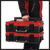 Personne portant deux caisses à outils Einhell rouges et noires empilées.