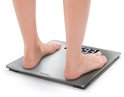 Voeten op een zilverkleurige digitale weegschaal die 59.3 aangeeft