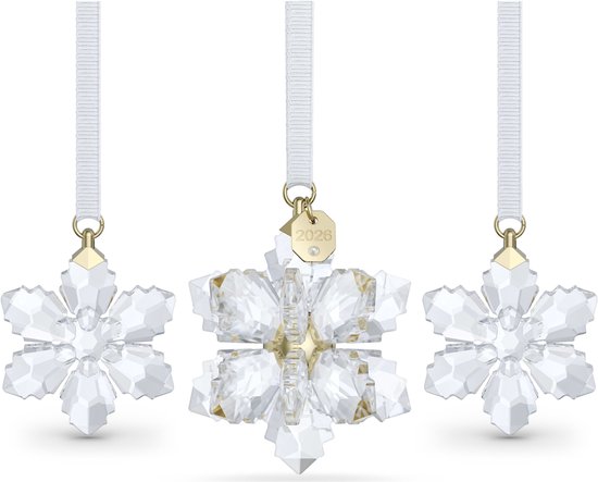 Drie kristallen kerstster hangers, de middelste met gouden label '2026'.