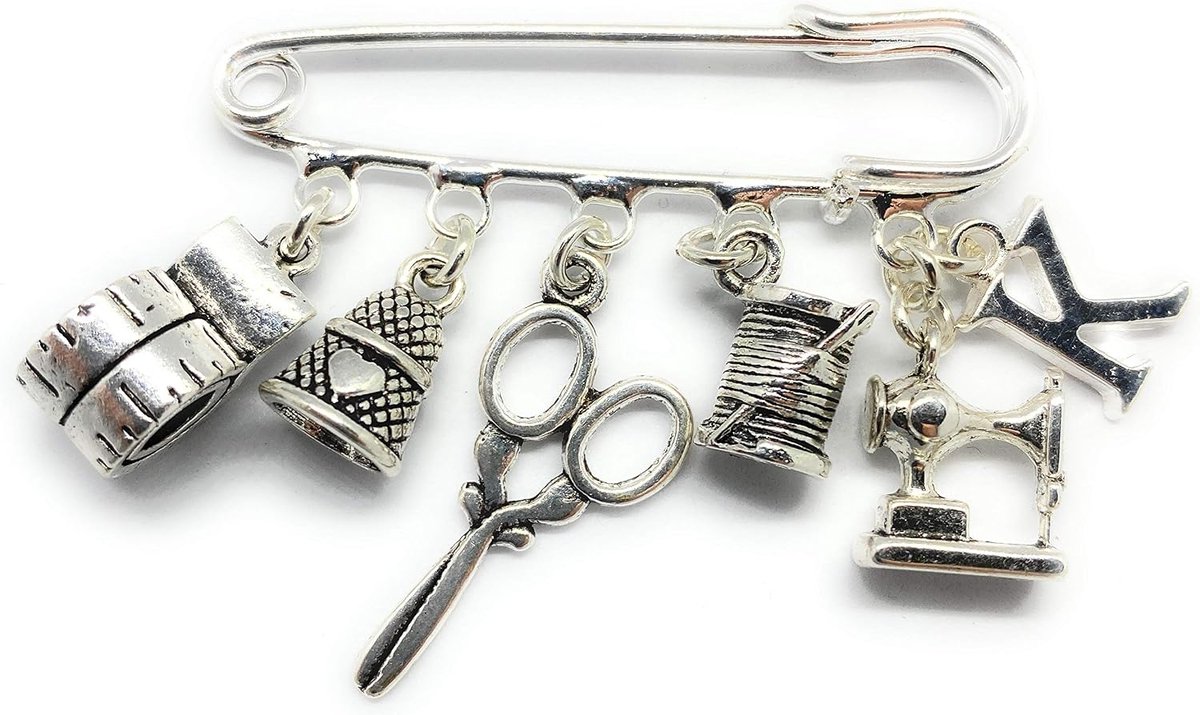 Naaister pin broche met naaimachine spoel schaar vingerhoedje meetlint en initiële bedels. De broche en bedels zijn verzilverd en van de hoogste kwaliteit.
