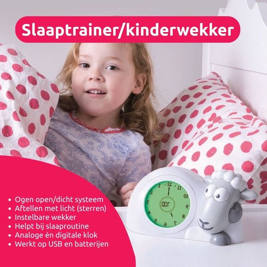 Grijze schaap slaaptrainer met analoge en digitale klok. Tekst: Slaaptrainer/kinderwekker, Ogen open/dicht systeem, Aftellen met licht (sterren), Instelbare wekker, Helpt bij slaaproutine, Analoge én digitale klok, Werkt op USB en batterijen.