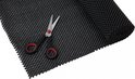 Zwarte antislipmat op rol met honingraatpatroon, met schaar erop.