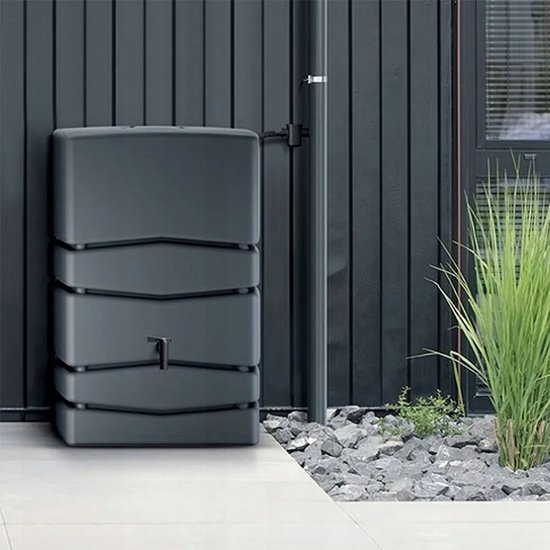 Antracietkleurige regenwatertank met ribbels, tegen een donkere schutting.