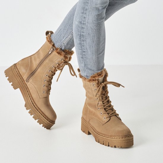 Model draagt beige suède enkellaarsjes met veters, ritssluiting en teddy voering in een jeans.