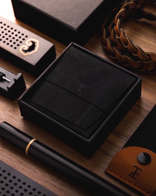 Een open zwarte geschenkdoos met een schuiminterieur, met een armband en een pen ernaast.