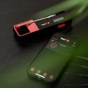 Een thermometer met app op een smartphone. De thermometer is zwart en rood, de smartphone toont de app.
