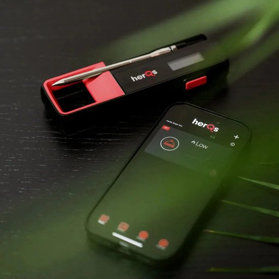 Een thermometer met app op een smartphone. De thermometer is zwart en rood, de smartphone toont de app.