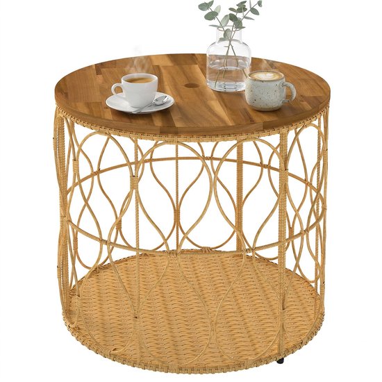Ronde teakhouten tafel met open, gevlochten rotan onderstel, met twee kopjes koffie en vaasje.
