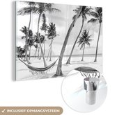 MuchoWow® Glasschilderij 150x100 cm - Schilderij acrylglas - Hangmat tussen palmbomen op het strand bij de Dominicaanse Republiek - zwart wit - Foto op glas - Schilderijen