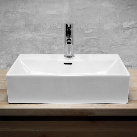 Lavabo rectangulaire en céramique blanche avec un robinet chromé, posé sur un plan de travail en bois.