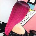 Vrouw met lang, golvend haar met een ombre-effect van donker naar felroze.