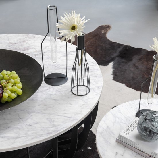 Deux tables d'appoint rondes, l'une avec un bol noir rempli de raisins et une structure en métal noir. L'autre table présente un livre.
