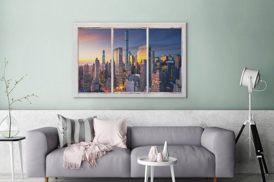 Toile avec vue sur la skyline de New York au coucher du soleil, accrochée au-dessus d'un canapé gris.