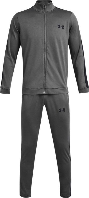 Man met grijze trainingsset: jack met zwarte strepen en logo, en broek met zwarte strepen en logo.