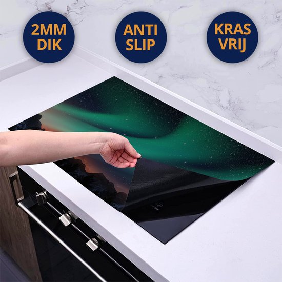Een hand plaatst een beschermmat met Noorderlicht-afbeelding op een inductiekookplaat.