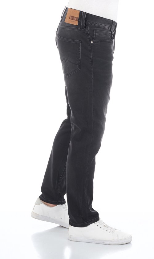 Man in donkergrijze tapered fit jeans van Mustang, zijaanzicht.