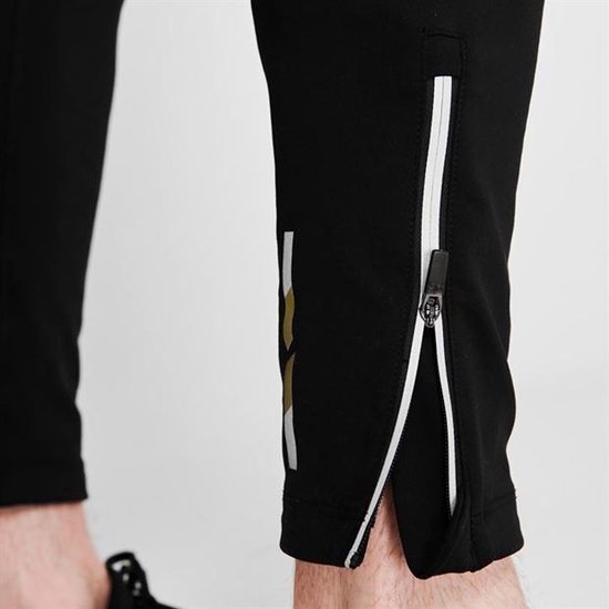 Close-up van de enkel van een zwarte Karrimor legging met rits en gestreepte details.
