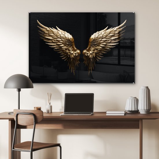 Gouden engelenvleugels op zwarte achtergrond, boven een bureau met laptop.