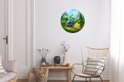Ronde muurdecoratie met een blauwe trein in een groen landschap, in een woonkamer.