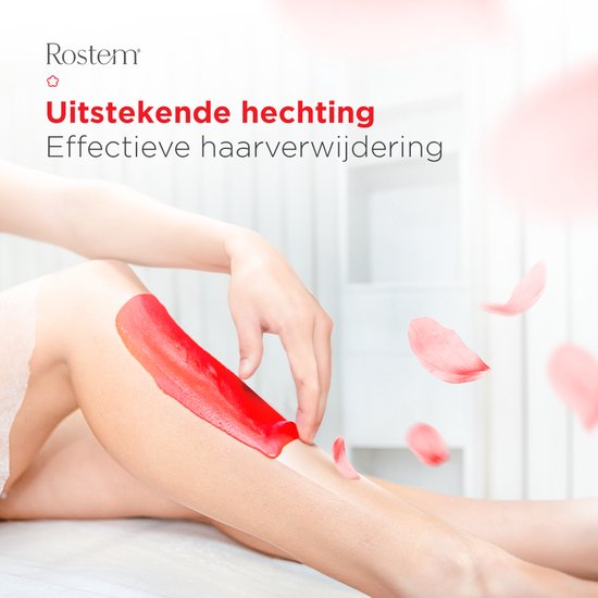 Gedetailleerde close-up van een vrouw die Rostem Hard Wax Beans op haar been aanbrengt, met rozenblaadjes die naar beneden zweven.