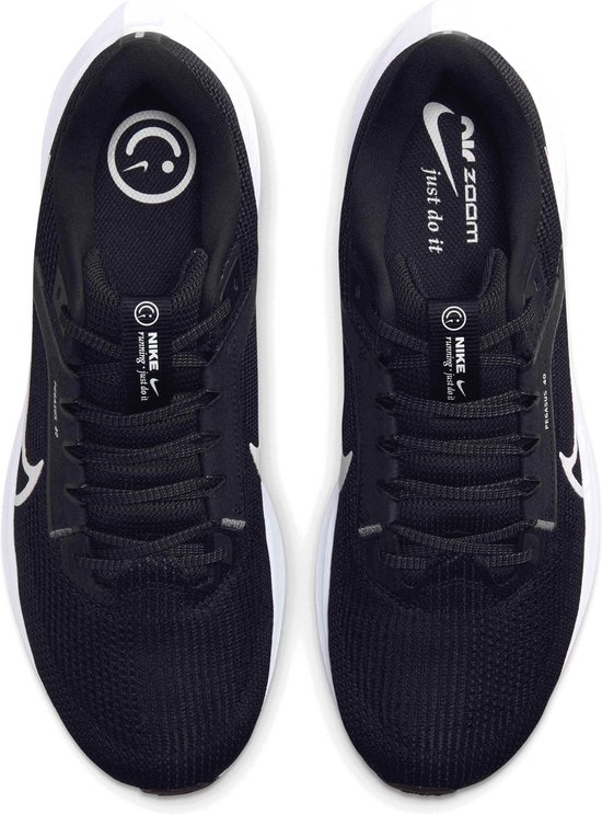 Bovenkant van zwarte Nike hardloopschoenen met witte veters en logo's.