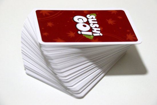 Een grote stapel witte speelkaarten met de rode achterkant van het spel 'Sushi Go!' bovenaan.