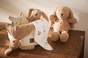 Een beige gebreid mandje met teddy konijntjes en een babyromper.
