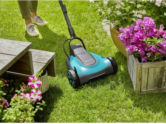 Dichtbij van een grastrimmer met blauw-grijze behuizing en wielen op het gras.