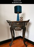 Turkooizen fluwelen tafellamp met schubbenpatroon op een antieke console.