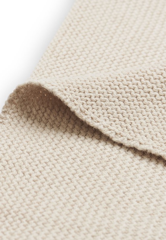 Gedetailleerde textuur van de beige gebreide stof van een babydeken.