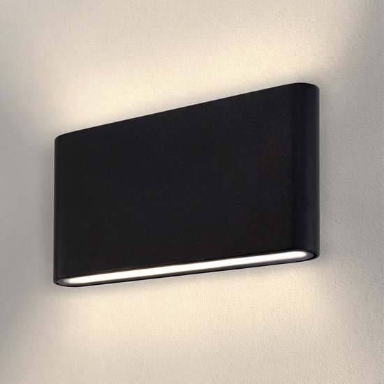 Applique murale noire arrondie fixée à un mur, émettant une lumière chaude dirigée vers le bas.