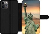 Bookcase Geschikt voor iPhone 11 Pro Max telefoonhoesje - New York - Vrijheidsbeeld - Zonsondergang - Met vakjes - Wallet case met magneetsluiting