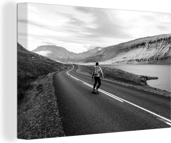 Canvas schilderij 150x100 cm - Wanddecoratie Een man op een skateboard bij een meer in IJsland - zwart wit - Muurdecoratie woonkamer - Slaapkamer decoratie - Kamer accessoires - Schilderijen