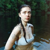 Een vrouw met lang, nat haar en een witte tanktop, omringd door donker water.