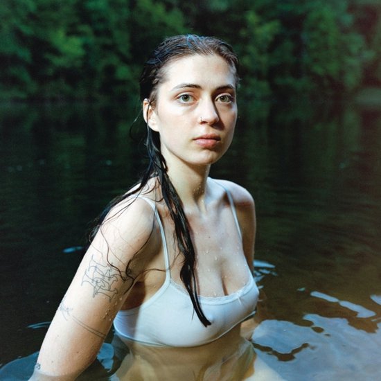 Een vrouw met lang, nat haar en een witte tanktop, omringd door donker water.